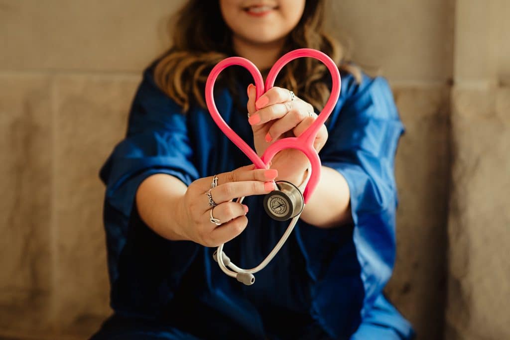 A woman with a stethoscope holding it to look like a heart