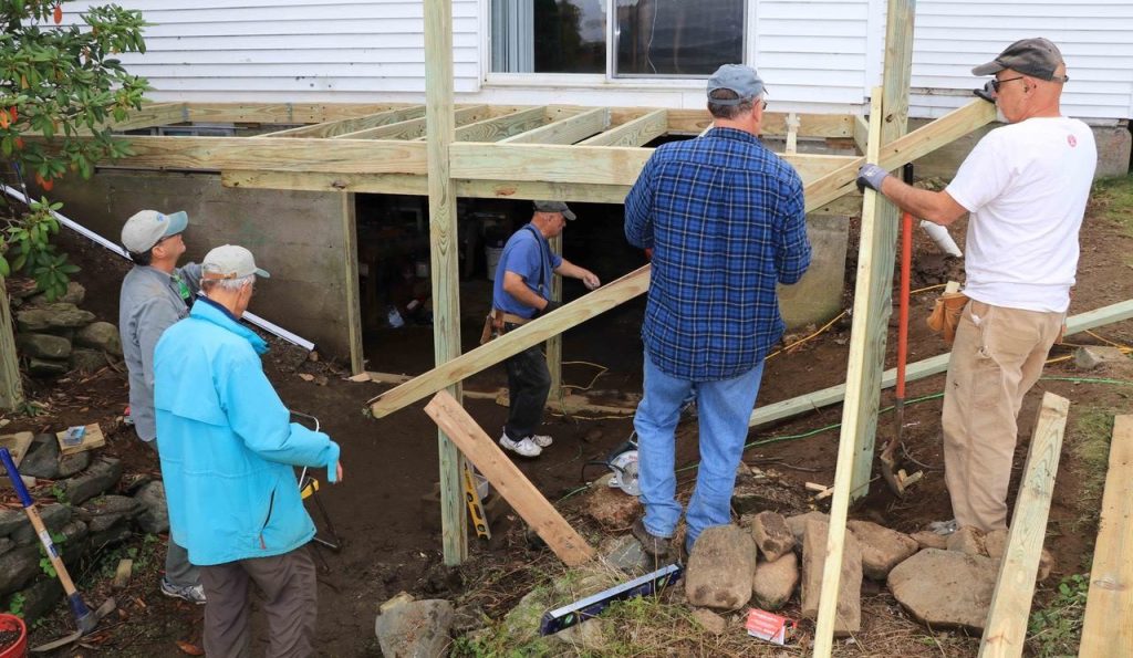 Several Men building a deck outside a home.