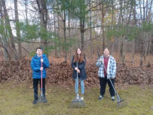 Harpswell Coastal Academy students pause for a photo while raking a Harpswell resident’s yard in fall 2022. From left: Ciaran Sandelin, Ella-Rose Biette and Ash Rank.