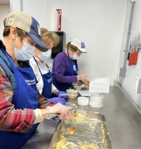 Cooking for Friends volunteers pack macaroni and cheese in the commercial kitchen at the Mid Coast Hunger Prevention Program in Brunswick. (Surrey Hardcastle photo)